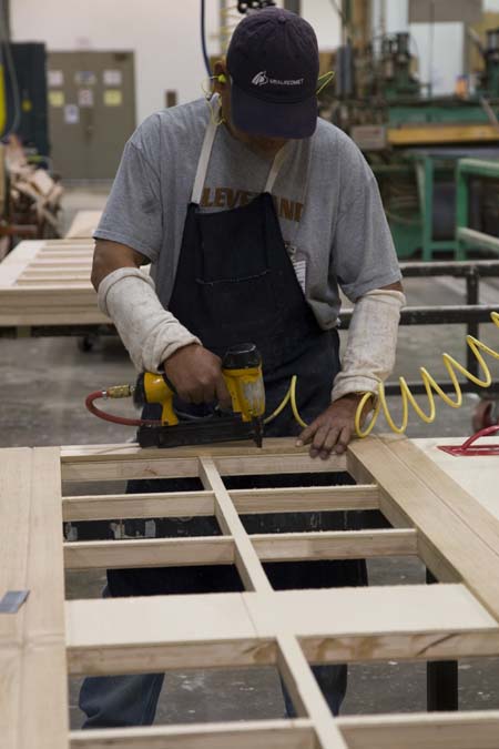 Artisan working on a wood garage door in Clopay’s wood manufacturing facility.